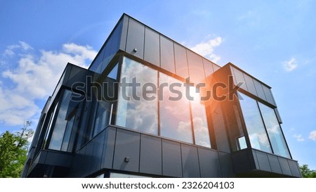 Graphite facade and large windows on a fragment of an office building against a blue sky. Modern aluminum cladding facade with windows. Royalty-Free Stock Photo #2326204103