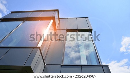 Graphite facade and large windows on a fragment of an office building against a blue sky. Modern aluminum cladding facade with windows.