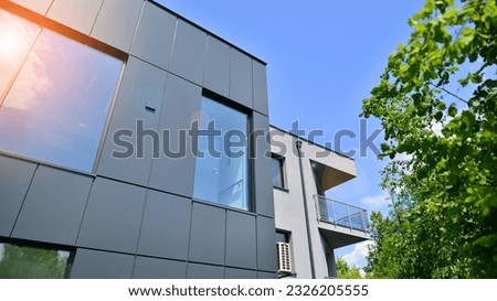 Graphite facade and large windows on a fragment of an office building against a blue sky. Modern aluminum cladding facade with windows.