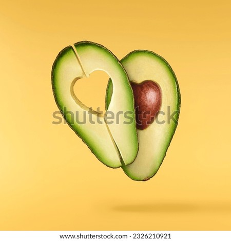 Fresh ripe avocado falling in the air isolated on yellow background