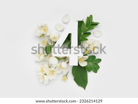 Green leaves and flowers with paper number four on white background