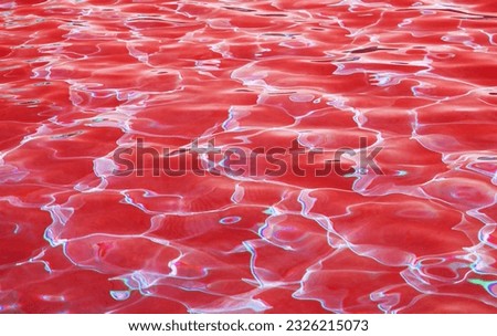 Eye-catching surreal pop art of red colored water surface reflecting with sunlight for abstract background