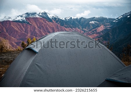 NagTibba, Snow capped Himalayan Mountain ridge with deep valley landscape view from a campsite. Camping and trekking in Uttarakhand.