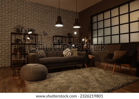 Interior of dark living room with cozy grey sofa and glowing lamps Royalty-Free Stock Photo #2326219801