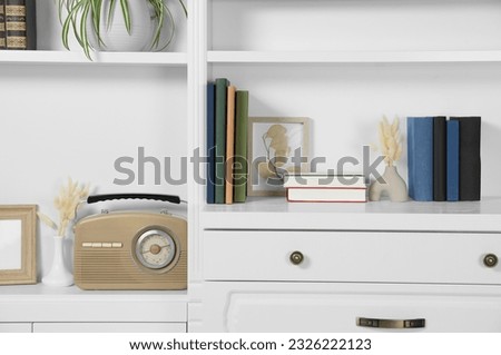 Hardcover books, decor and vintage radio on shelving unit