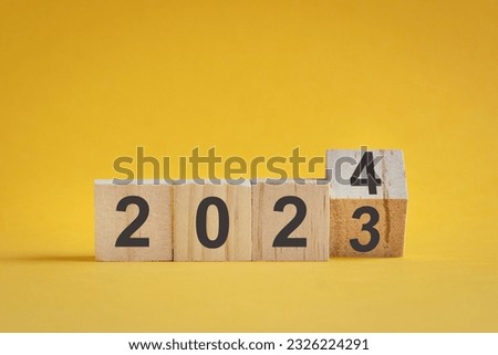 Wooden cube stock flipping, change from 2022 to 2023. Yellow color background, with copy space. Royalty-Free Stock Photo #2326224291