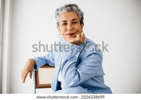 Female professional looking at the camera in her office. Dressed in a professional suit and grey hair, she expresses her confidence and empowerment as an experienced and accomplished business woman. Royalty-Free Stock Photo #2326238699