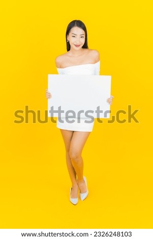 Portrait beautiful young business asian woman with empty white billboard card on yellow background