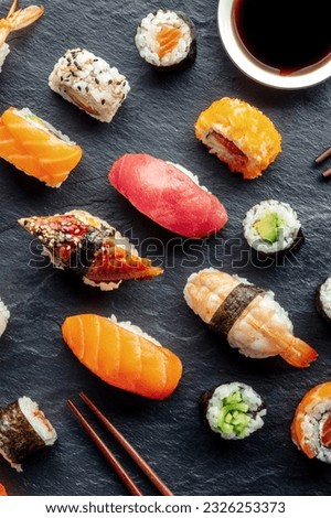 Sushi, shot from the top with chopsticks and soy sauce. Rolls, maki, nigiri on a black background, Japanese food. Salmon, tuna, eel, shrimp and other seafood