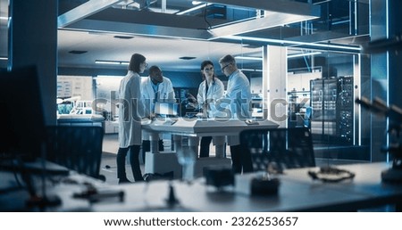 Team of Industrial Engineers Working on a Bionic Robot Arm at a Startup Factory. Multiethnic Male and Female Scientists Having a Conversation About an Electronic Component for a Humanoid AI Robot Royalty-Free Stock Photo #2326253657