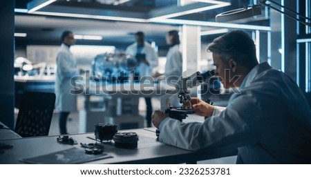 Diverse Multiethnic Team of Industrial Engineers Gathered Around Table With Prototype Turbine Engine. Scientists Use Tablet Computer and Microscope to Research, Develop and Program Futuristic Motor. Royalty-Free Stock Photo #2326253781