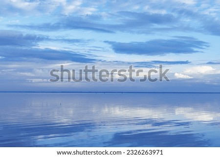 White blue clouds over lake, symmetric sky and water background, cloudscape on lake. Nature abstract, cloudy sky reflected on still water, calm tranquil concept, aesthetic panoramic view