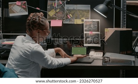 Young inspector using greenscreen in archive office space, examining chroma key display and conducting investigation. Detective checking isolated mockup template with copyspace.