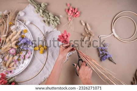 Cut dried flowers with scissors, make wreath with colourful dried flowers, preparation Royalty-Free Stock Photo #2326271071
