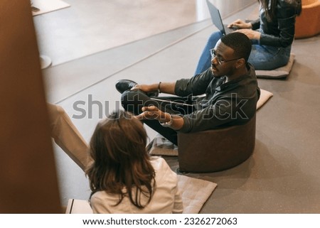 Handsome black male employee gesticulating with hand while explaining Royalty-Free Stock Photo #2326272063