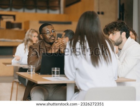 Handsome male diverse male business coworkers listening to their female colleague explaining something about the new project