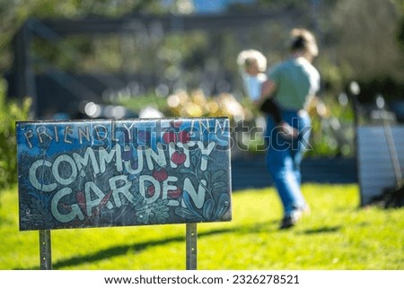 community garden sign at a vegetable garden with a mother and baby in a city garden in australia in spring
