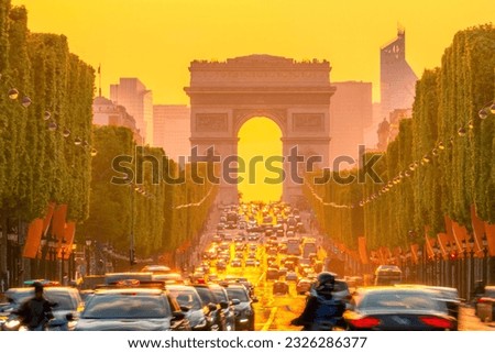France. Paris. Dense traffic on the Champs Elysees. Triumphal Arch on a background of orange sunset
