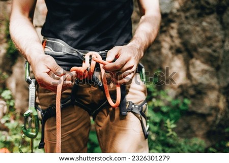 Male rock climber with climbing equipment holding rope ready to start climbing the route Royalty-Free Stock Photo #2326301279