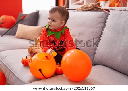 Adorable hispanic baby having halloween party wearing pumpkin costume at home