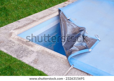 Garden pool is closed with a protective canvas when autumn arrives and prevents water evaporation and excessive soiling until the next summer season. Royalty-Free Stock Photo #2326315691