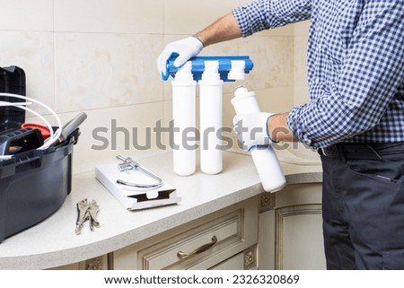 Water purification filter install. Handyman man in workwear installing water filtration system. Royalty-Free Stock Photo #2326320869
