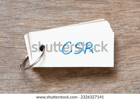 Flash card with handwriting in word CSR (Abbreviation of corporate social responsibility) on wood background