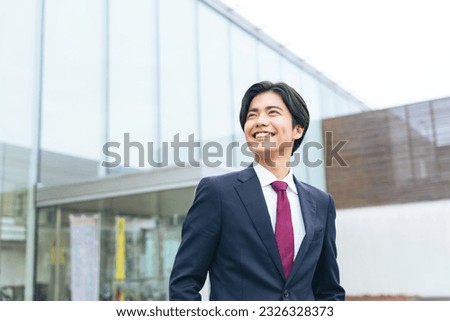 Young Asian businessman standing in front of office building.