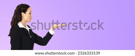 Ad photo - profile side of young businesswoman show, hold, give, demonstrate, advertising product. Business woman looking at her hand in studio concept, isolated violet purple background. 