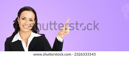 Ad photo - happy smiling woman wear confident suit, show aside point finger advertise promo. Business concept. Isolated violet purple color background. Brunette businesswoman. Wide banner composition.