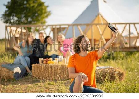 Happy group of friends multiracial Very charismatic taking selfies with smartphone hugging all each other and sitting down on the haystack