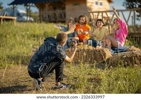 Group of handsome and charismatic friends multiracial at campsite taking pictures with smartphone posing and chilling at the same time
