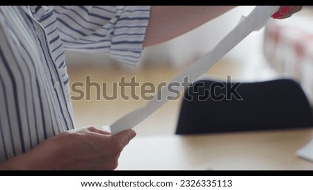 Close-up woman hands pull out paper envelope utility bill paper letter bank documents. Woman hands opening paper letter post invoice tax forms.