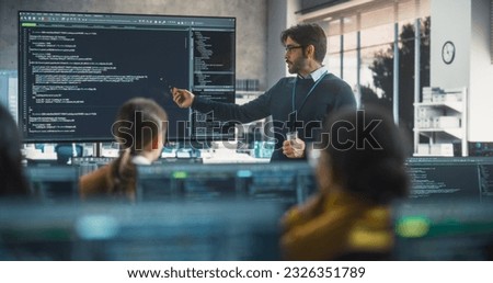 Teacher Giving Computer Science Lecture to Diverse Multiethnic Group of Female and Male Students in a College Room. Projecting Slideshow with Programming Code. Explaining Information Technology Royalty-Free Stock Photo #2326351789