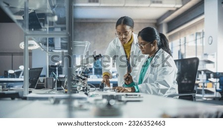 Indian Girl Having a Conversation with a Mentor in a Laboratory, While Working on a Circuit Board for a Project. Young Scholar Talking with a Scientist About Changing the CPU Memory Characteristics