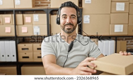 Young hispanic man ecommerce business worker having video call holding package at office