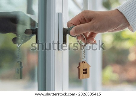 Landlord key for unlocking house is plugged into the door. Second hand house for rent and sale. keychain is blowing in the wind. mortgage for new home, buy, sell, renovate, investment, owner, estate Royalty-Free Stock Photo #2326385415