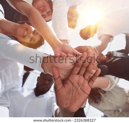 multinational business team looking down putting hands together