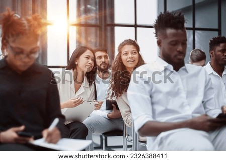 Multi-ethnic group of people while answering questions during training seminar or business conference in office, copy space