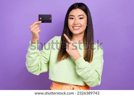 Photo of adorable cheerful woman dressed green clothes indicating at plastic card good proposition isolated on purple color background