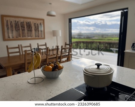 Pot on hob with fruit and countryside view out of bifold doors with dining table Royalty-Free Stock Photo #2326390685