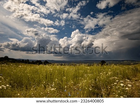 Storm over the meadows with a dark sky and a big cumulonimbus thundercloud Royalty-Free Stock Photo #2326400805