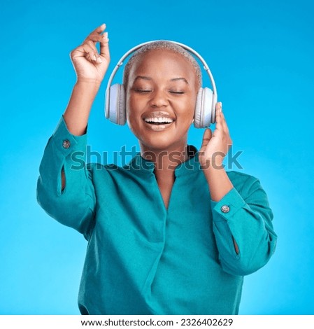 African woman, headphones and studio for dancing, music or listen with smile by blue background. Young gen z student, sound tech and happy for audio streaming subscription, radio or excited for dance