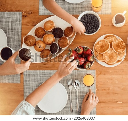 Breakfast, food and hungry people in dining room, eating healthy and above table setting or home in the morning. Fruit, pancakes and hands on strawberry or muffin plate for nutrition or diet