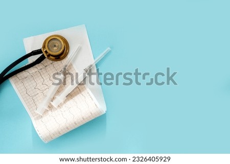 phonendoscope, cardiogram, syringes on a blue background with copy space, modern medicine.