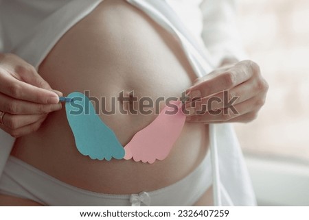 pregnant woman holding card with boy or girl decoratoin feet, gender reveal surprise party Royalty-Free Stock Photo #2326407259