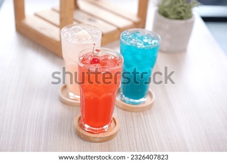 Refreshing cold beverage for summer on ice. Colorful summer drink in tall glass with wood saucer for hot day and party.