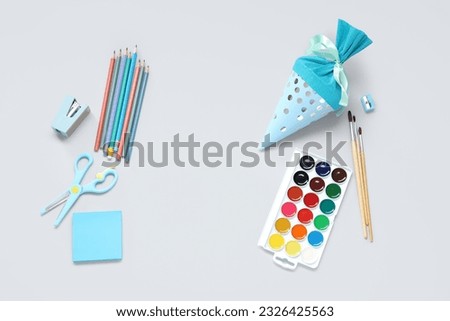 Blue school cone with different stationery on grey background