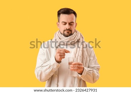 Ill young man with soluble tablet and glass of water on yellow background