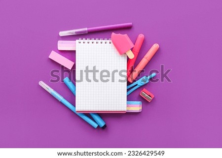 Blank notebook with different stationery on purple background